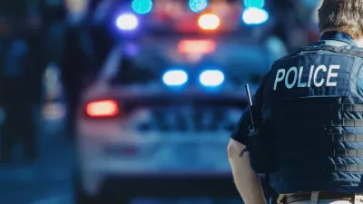 Police officer with POLICE on the back of their vest with police car in the background