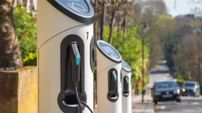Row of curbside electric vehicle chargers with black car approaching in background