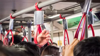 Close-up of bus passengers hanging on to red straps on crowded bus