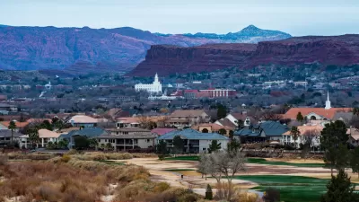 Town of St. George, Utah with small white church and red rock cliffs in background