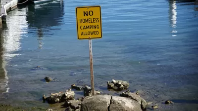 Yellow "no homeless camping" sign in water at California beach