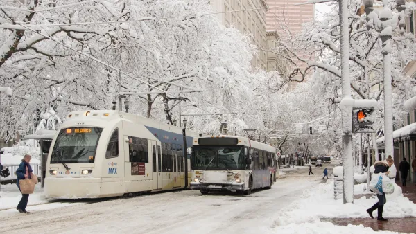 TriMet bus next to Max light rail train on snowy street in Portland, Oregon.