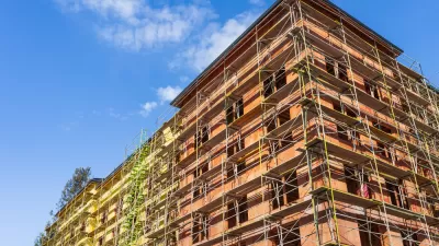 Multistory wood frame apartment building under construction against blue sky