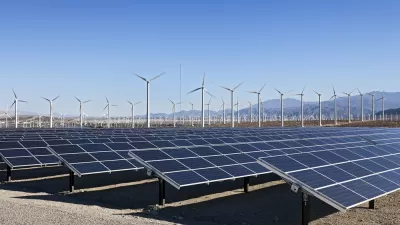 Solar array and wind turbines in California with mountains in background