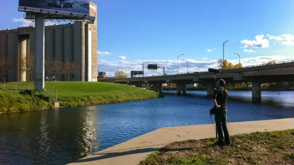Man standing on riverbank in Montreal holding up sound measuring equipment.