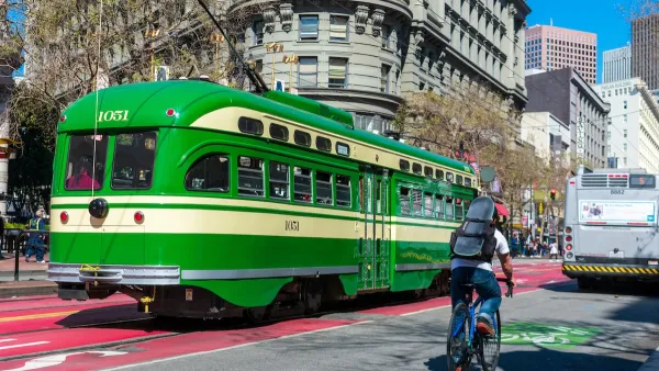 Bright green vintage streetcar and cyclist on Market Street in San Francisco, California.