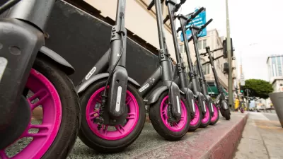 Low close-up shot of black and pink Lyft e-scooters lined up on downtown Los Angeles sidewalk
