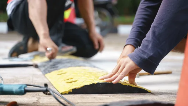 Close-up of people;s hands installing black and yellow road hump.