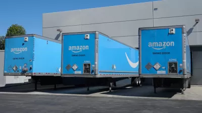 Three blue Amazon delivery trucks at bays at a distribution center