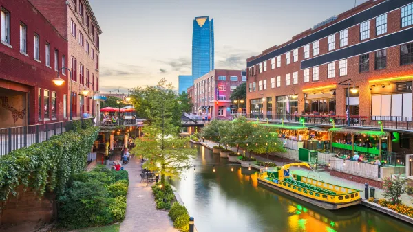Canal in downtown Oklahoma city with outdoor dining patios on either side and tall modern skyscraper in background.