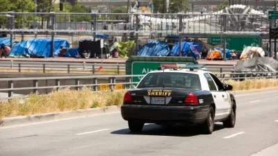 Homeless encampment on overpass in downtown Los Angeles with police car in foreground