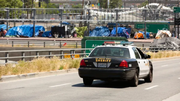 Homeless encampment on overpass in downtown Los Angeles with police car in foreground