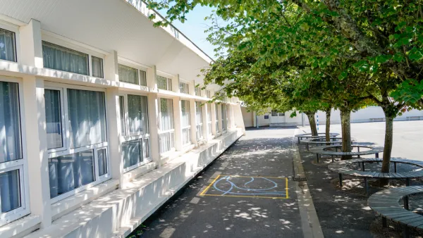 Schoolyard with leafy green trees surrounded by benches 