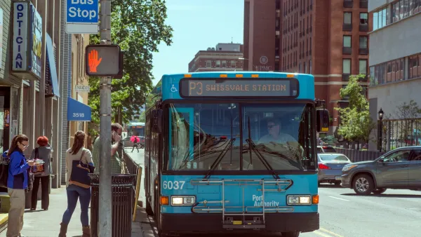 Blue Pittsburgh city bus stopped at a station on street.