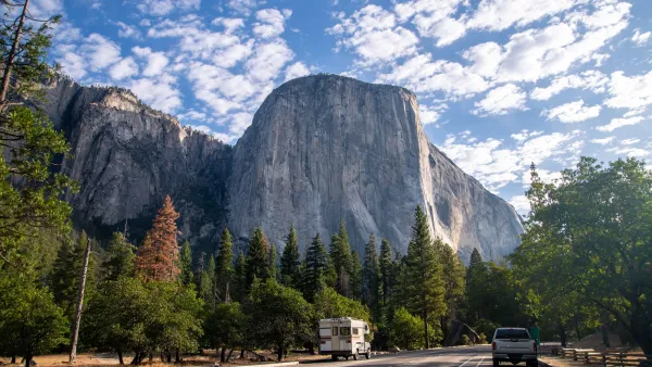 Road in Yosemite National Park with Half Dome rock formation looming above.