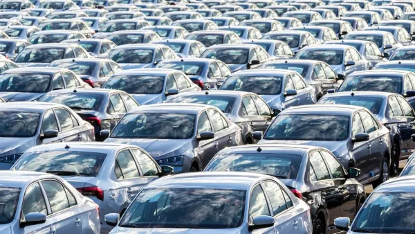 Dozens of cars parked in rows in an open-air parking lot.