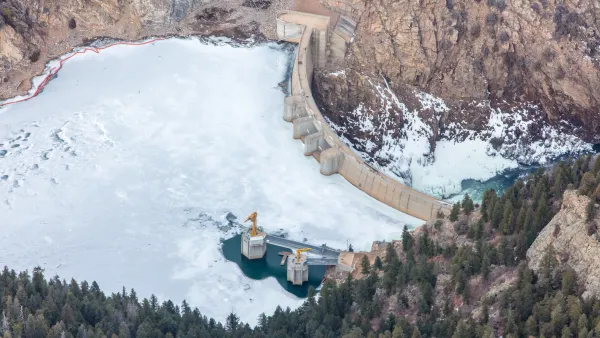 An aerial photo of Strontia Springs Reservoir. Most of the Reservoir is covered In ice. A stone wall blocks the water from flowing downstream.