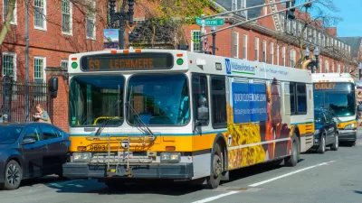 White and yellow MBTA bus in Cambridge, Massachusetts with brick buildings in background