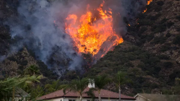 Large, orange fire burning on hillside behind SPanish-style homes in Azusa, California.