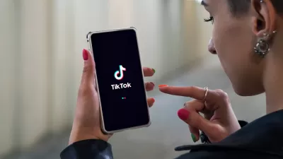 Woman holding phone with TikTok logo