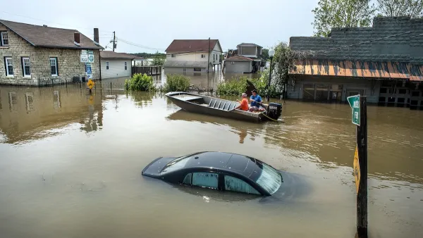 Submerged black car and people in small boat in flooded neighborhood in Grafton, Illinois.