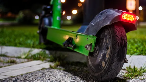 A green e-scooter at night with a red light on