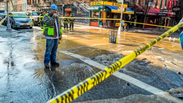Utility worker stands in flooded New York City intersection roped off with yellow caution tape speaking on walkie talkie.