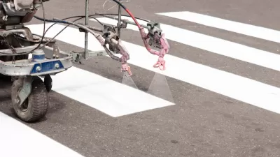 Machine spraying white crosswalk lines on street
