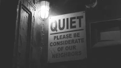 "QUIET Please be considerate of our neighbors" sign on outside of building with dim light