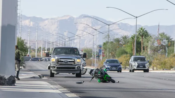 A green motorcycle lays crashed in a roadway with a large Ford pickup truck behind it in Las Vegas, Nevada.