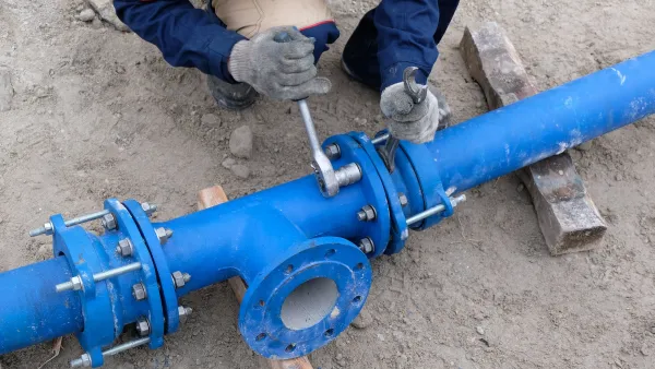Worker working on exposed blue water pipe.