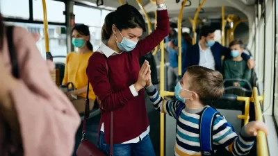Smiling mother and child on busy public bus wearing Covid-19 protective masks