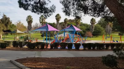 View of park playground with palm trees in background