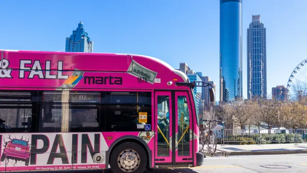 Pink MARTA public transit bus with Atlanta downtown skyline in background.