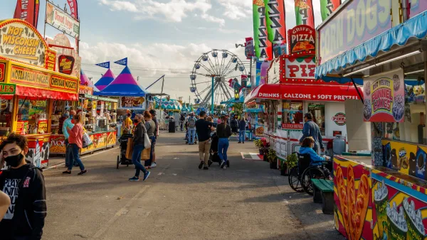 Amusement park boardwalk in Palm Beach, Florida with colorful booths and Ferris wheel.