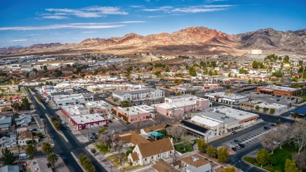 Aerial of small town in Nevada with mountains and bright blue sky in background.