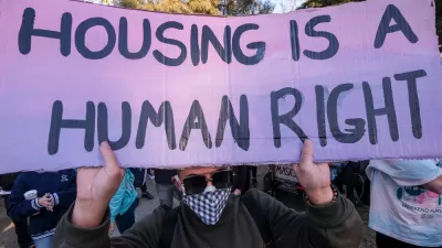 Protester at Echo Park Lake, Los Angeles holding sign that says "Housing is a human right"