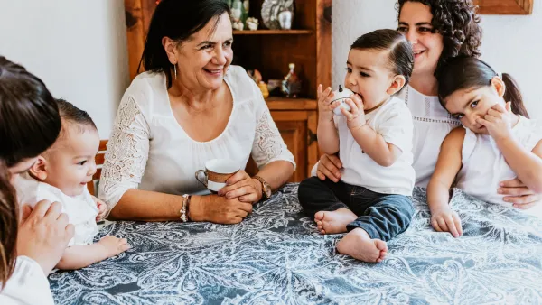 Mother with children sitting next to older woman/grandmother at table.