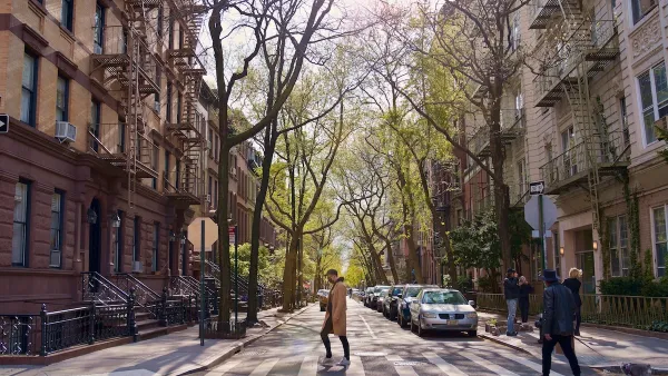 A person crossing the street between two residential buildings in NYC.