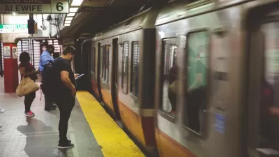 Passengers on Boston subway platform with blurred speeding train passing by