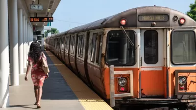 Orange Line train pulling into station with one woman waiting to board in Boston, Massachusetts