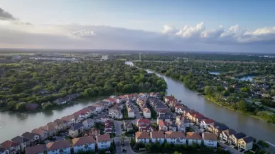Aerial view of neighborhood with homes along a bayou surrounded by green trees in Sugar Land, Texas