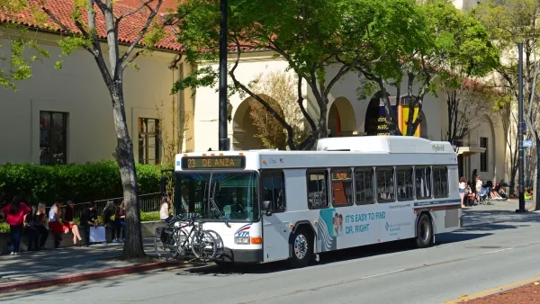 White San Jose city bus on street with Spanish-style architecture.