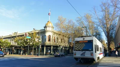 White VTA light rail train passing by historic building in downtown San Jose, California
