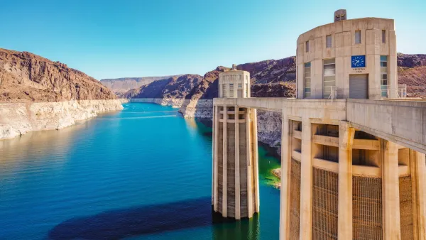 View from Hoover Dam of dam columns and Colorado River with water line visible above the water.