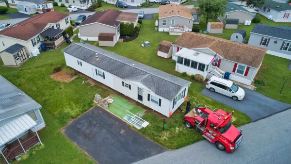 Aerial of manufactured homes being dropped off by red tractor.