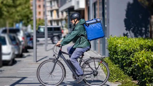Man riding e-boike wearing large blue delivery backpack.