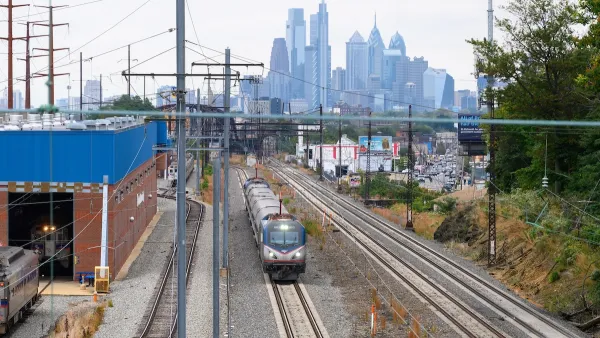 Amtrak train on tracks with Philadelphia, Pennsylvania skyline in background.