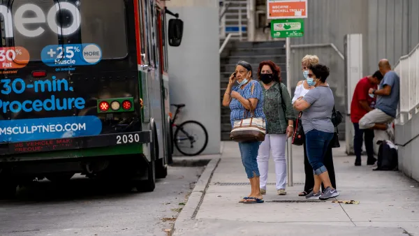 Group of women wearing masks during pandemic era standing at bus stop in Miami.