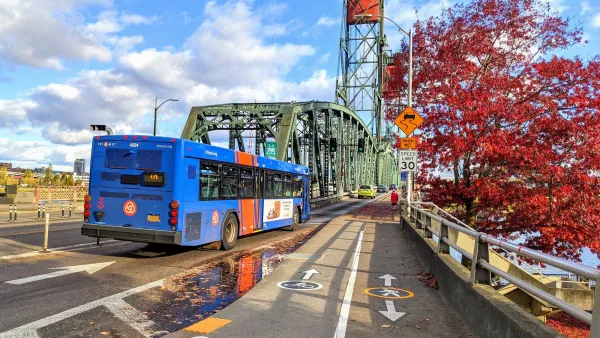 Blue TriMet transit bus driving across green steel bridge in Portland, Oregon.